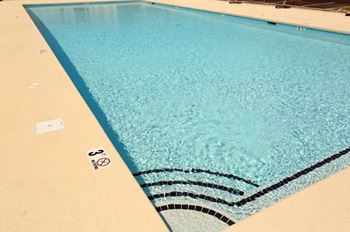 A swimming pool with a blue tiled edge and a white sign on the side.