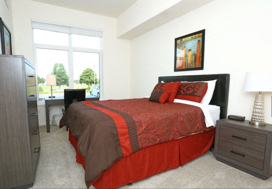 a bedroom with a bed and a desk and a window