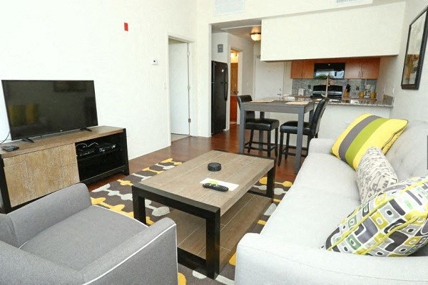 a living room and kitchen with a couch and a tv