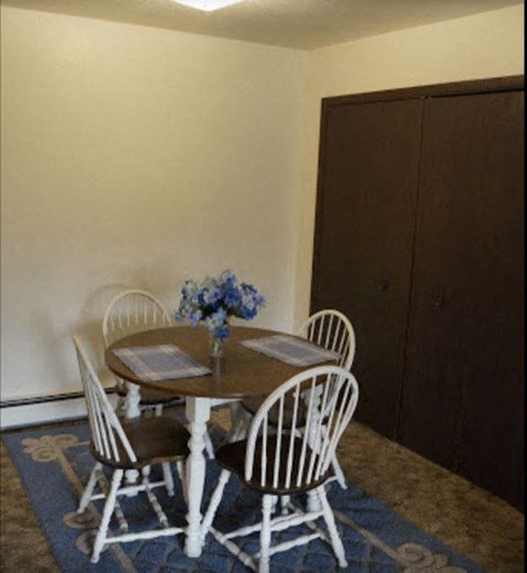 a dining room table with white chairs and a blue rug