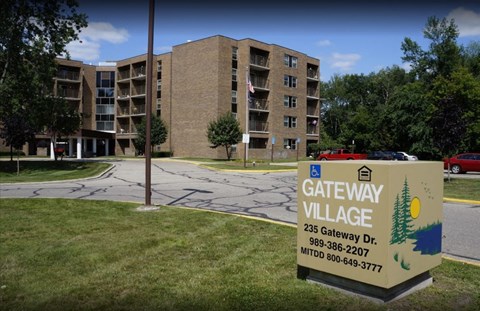 A sign for Gateway Village is in front of a building.