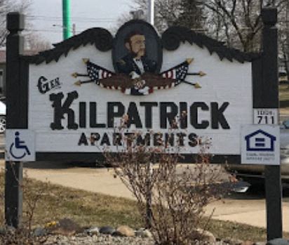 A sign for Kilpatrick Apartments is displayed in front of a parking lot.