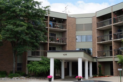 Apartment building with balconies and flower pots in front.
