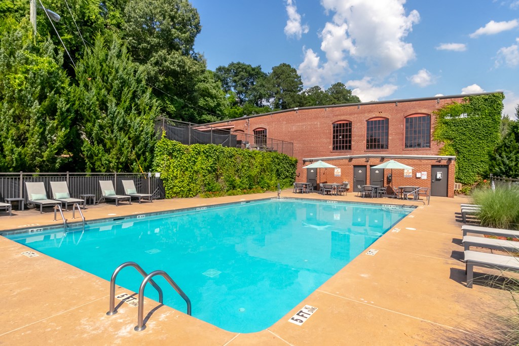 a swimming pool with chairs and a building in the background