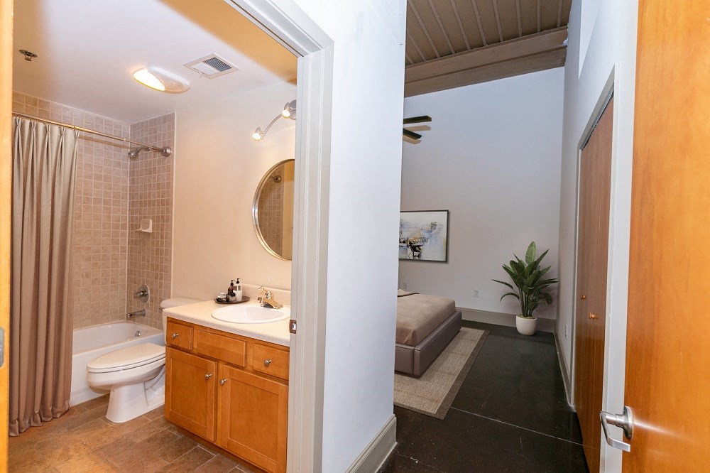 a bathroom with a sink toilet and shower and a bed