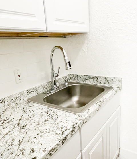 a sink in a kitchen with granite counter top and a faucet