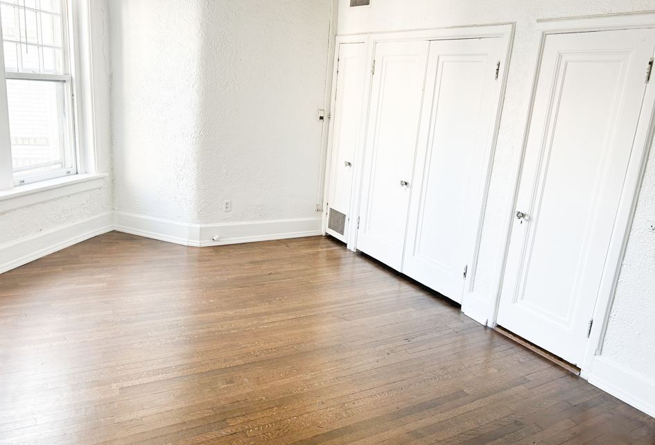 an empty room with wooden floors and white closets