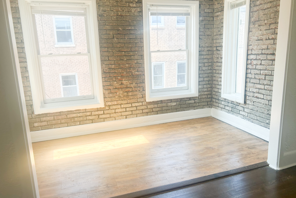 an empty room with three windows and a wooden floor