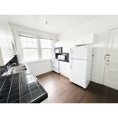 A kitchen with a black tiled counter and white appliances.