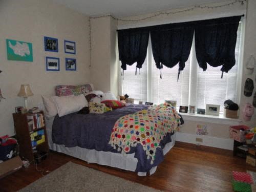 a bedroom with a bed and windows with black curtains