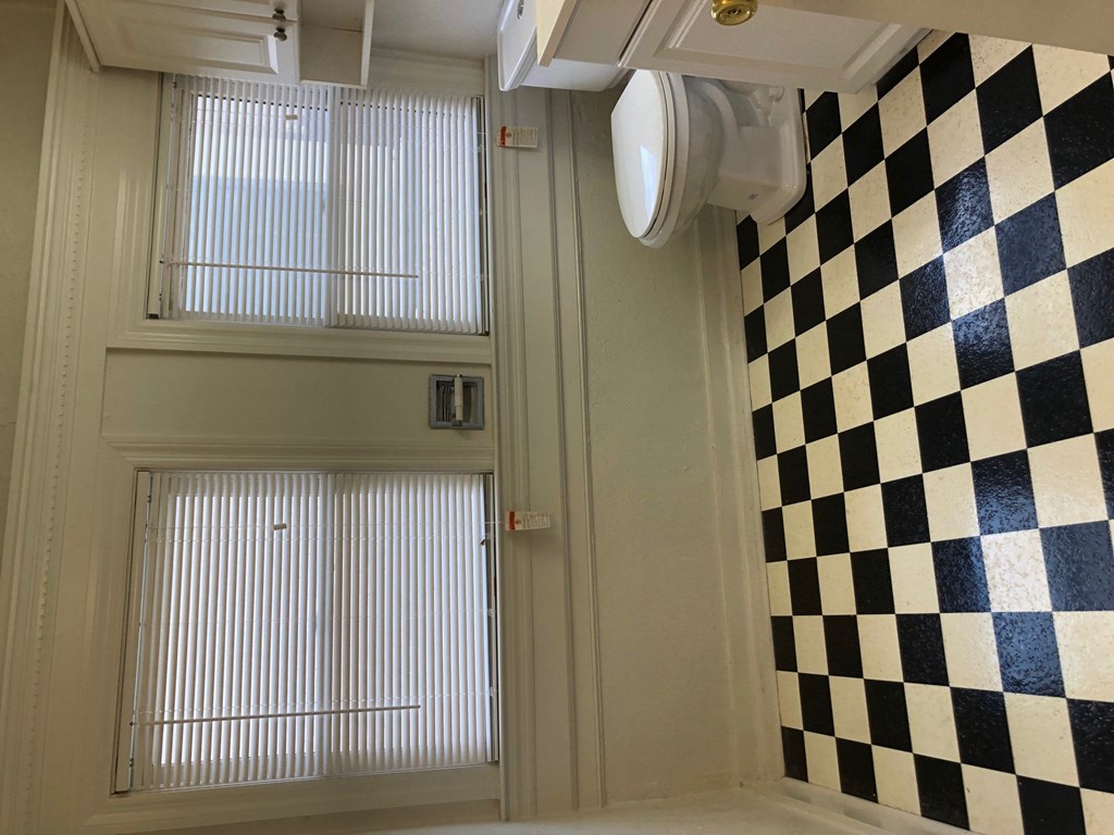 a bathroom with a toilet and a black and white checkered wall