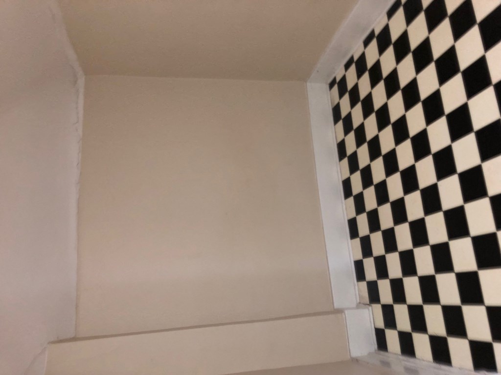 a room with a black and white checkered floor and a white wall