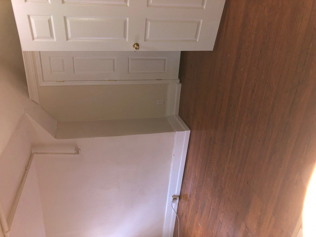 the top of a closet with a white door and a wooden floor