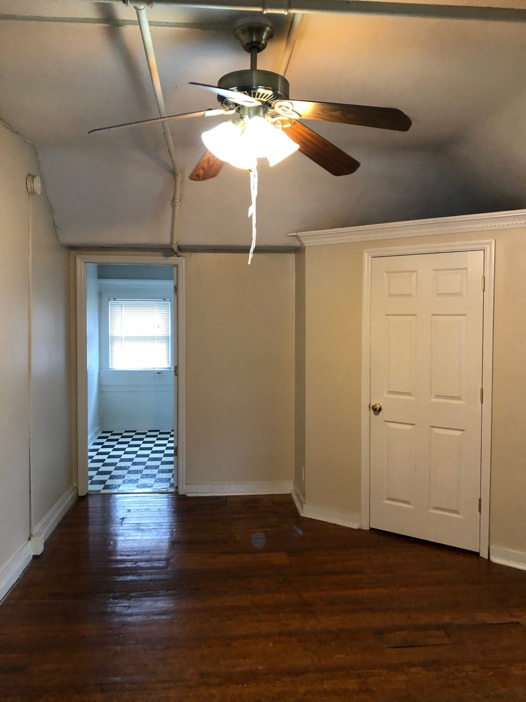a bedroom with a ceiling fan and a door to a bathroom