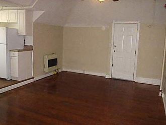 an empty living room with a microwave and a refrigerator