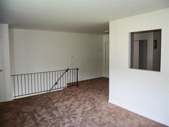 an empty living room with a staircase and a window