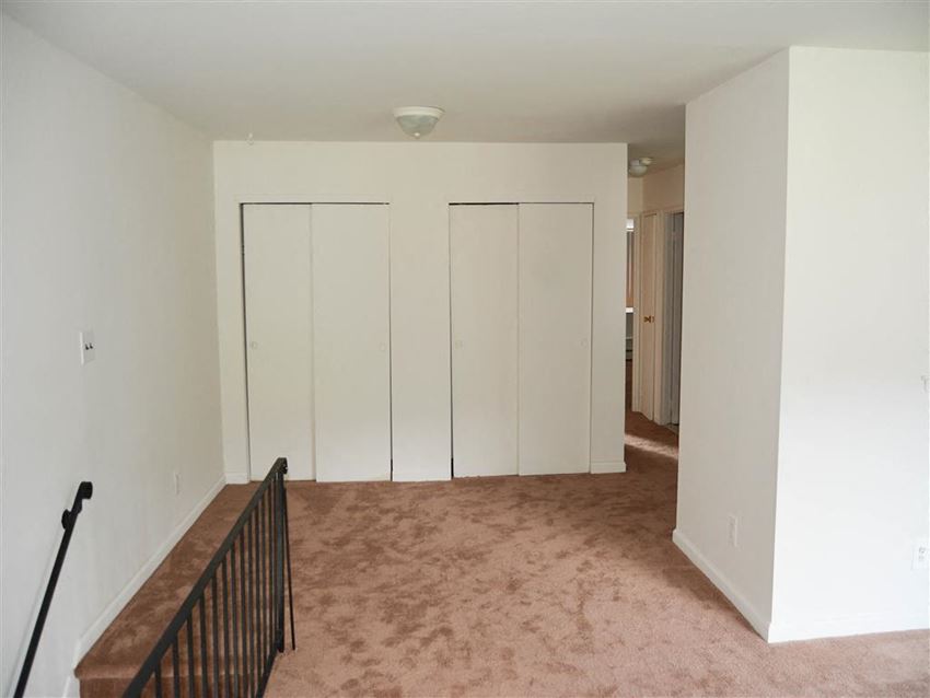 an empty living room with white walls and a staircase