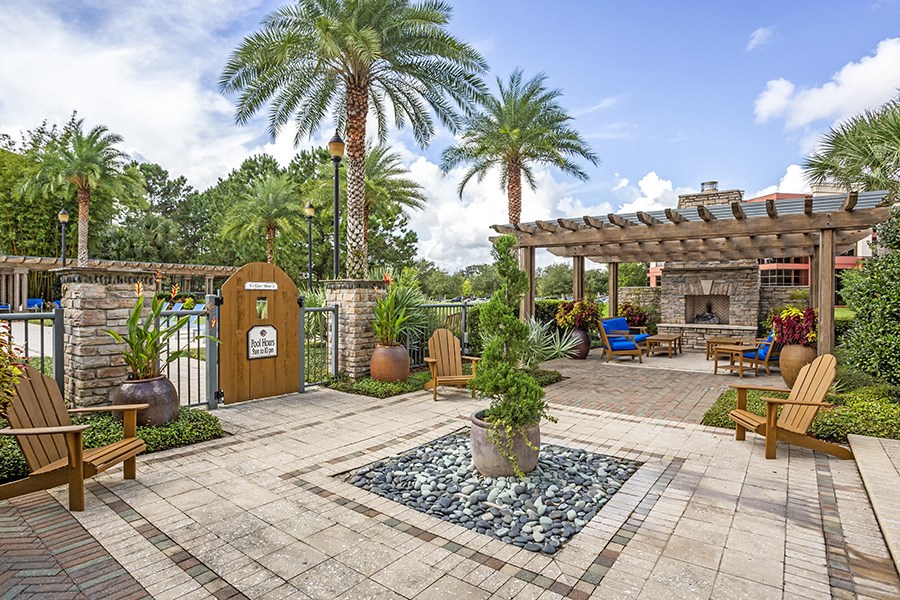 a backyard with a fire pit and a pergola with palm trees