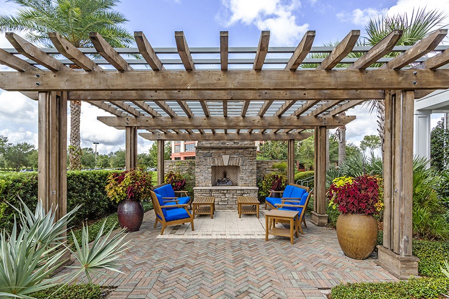 a patio with a stone fireplace and a wooden pergola