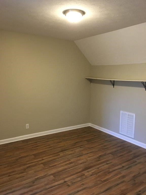 an empty room with a wood floor and a ceiling light