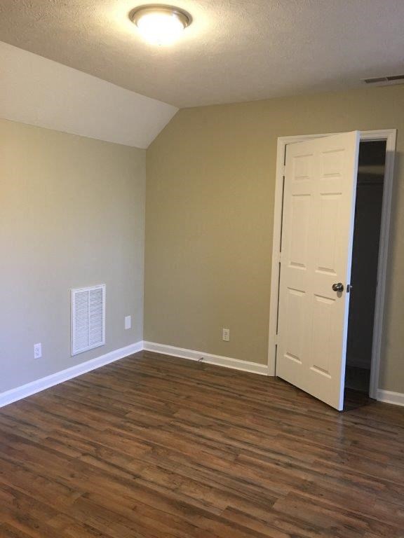 an empty room with a white door and wood floors