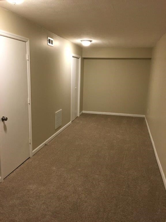 a empty room with a carpeted floor and a door