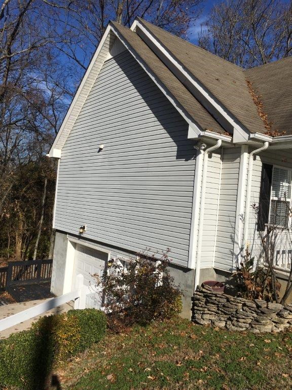 a white house with white siding and a stone wall