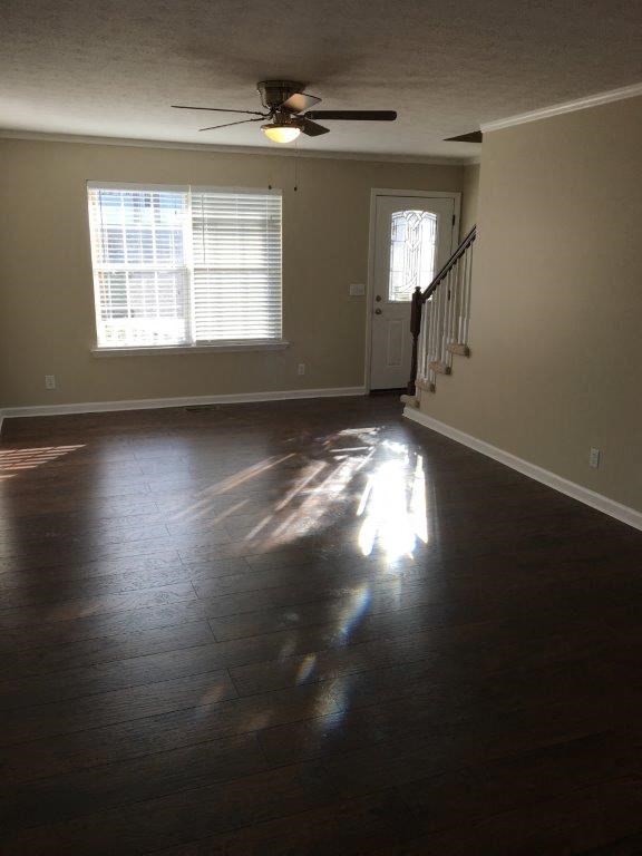an empty living room with a ceiling fan and a window