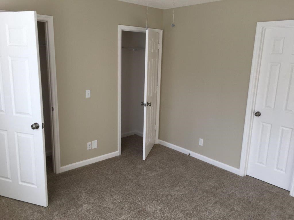 a room with a carpeted floor and a closet and two doors