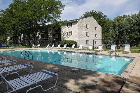 a swimming pool with chairs and a building in the background