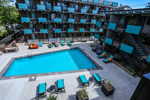 an overhead view of a resort style pool with blue lounge chairs