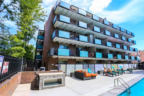 an apartment building with a pool and lounge chairs in front of it
