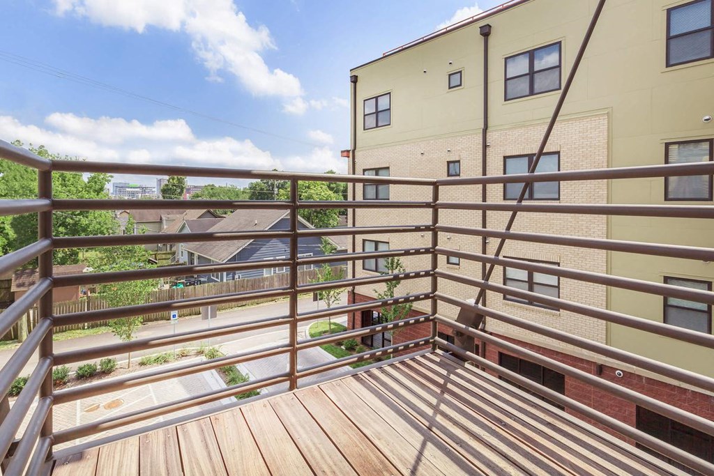 a balcony with a wooden deck and a brick building