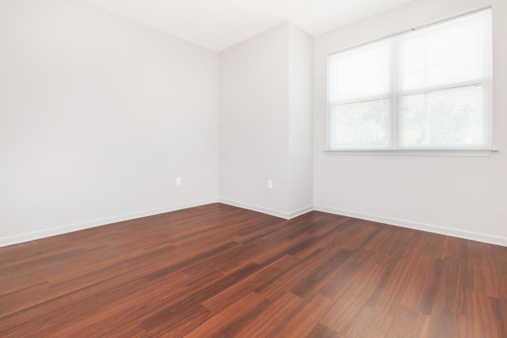 an empty room with wood floors and a window