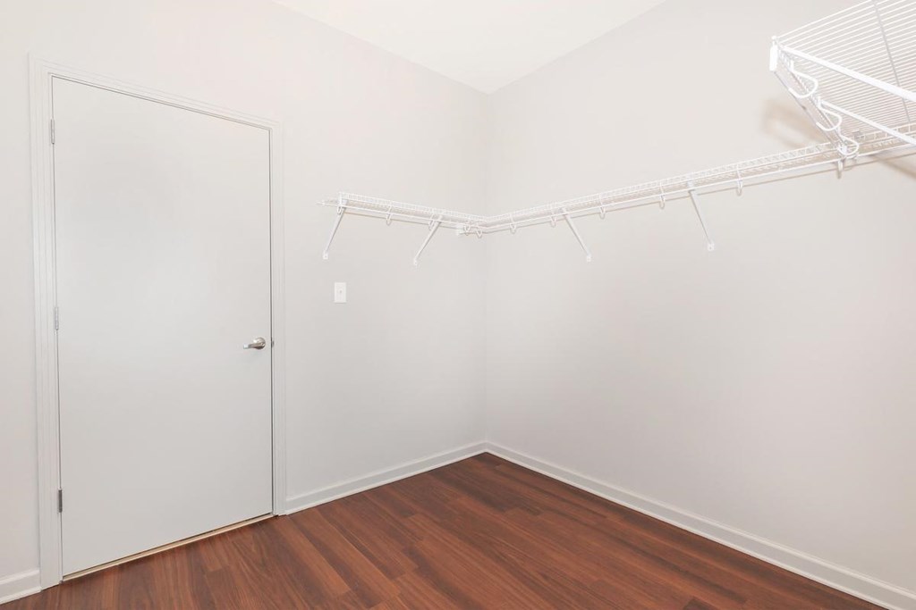 a bedroom with white walls and wood flooring and a closet