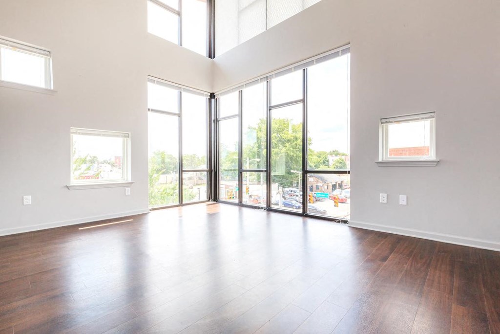 an empty living room with wood floors and large windows