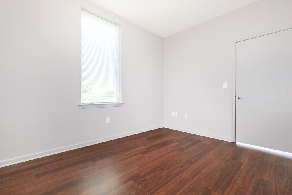 an empty room with wood floors and a window