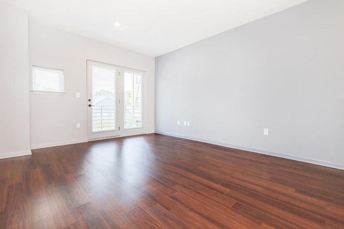 an empty living room with wood floors and a door