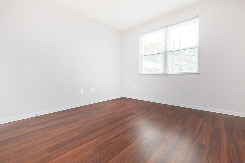 an empty room with wood floors and a window