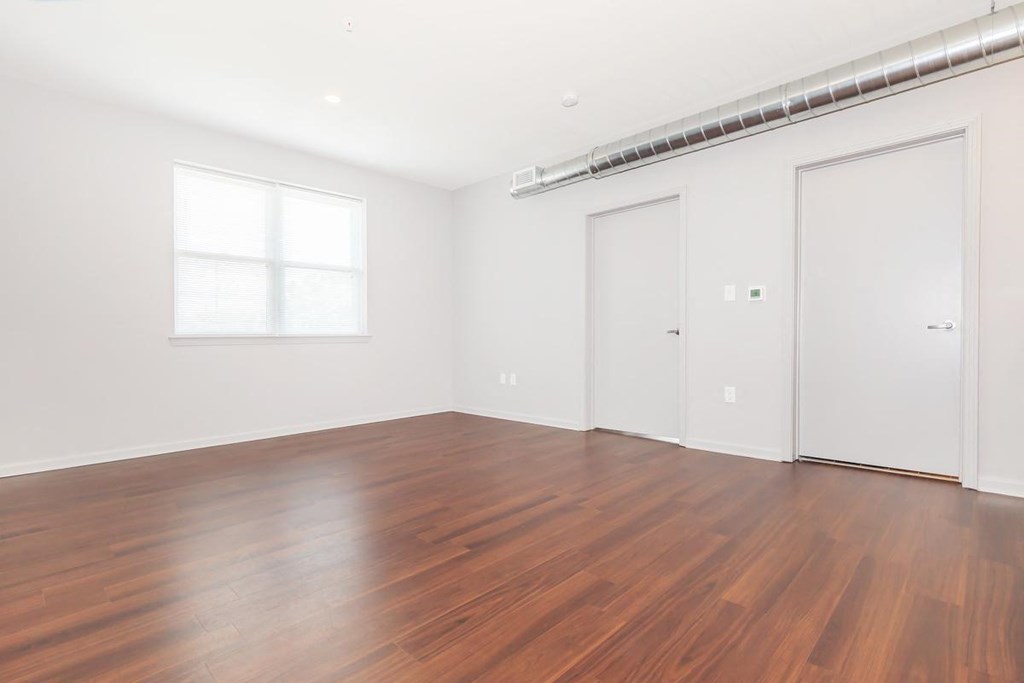 an empty living room with wood floors and white walls