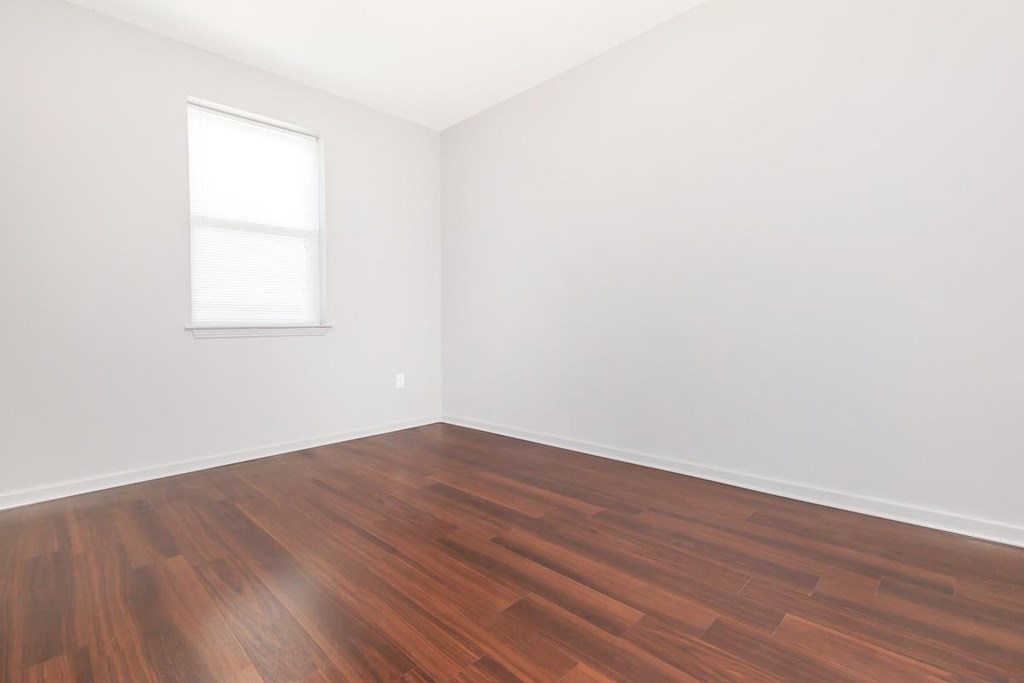 an empty room with wood floors and a window