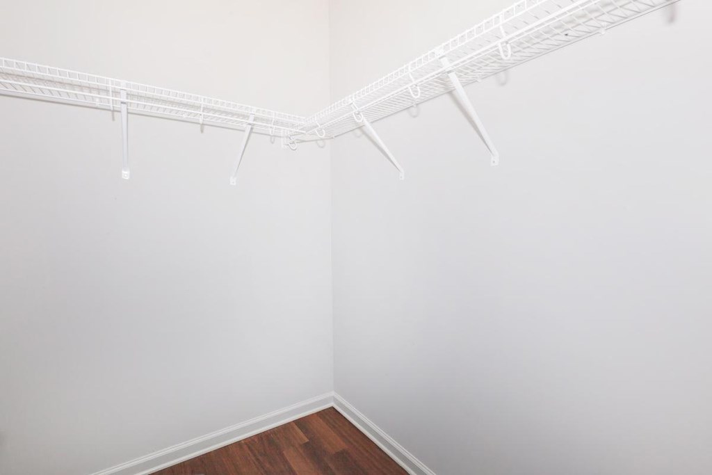 a closet with white walls and a wood floor