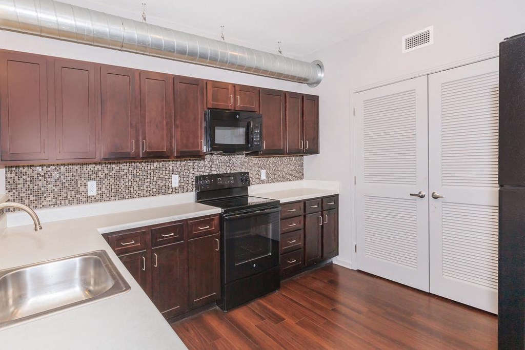 an empty kitchen with wooden cabinets and black appliances