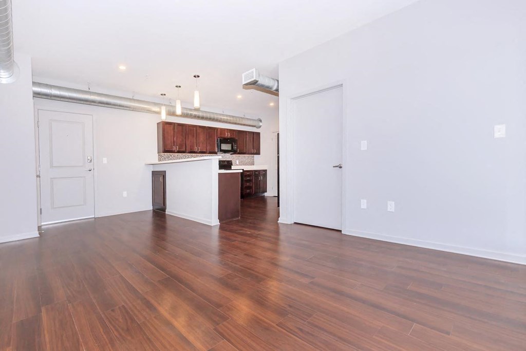 an empty living room and kitchen with wood flooring