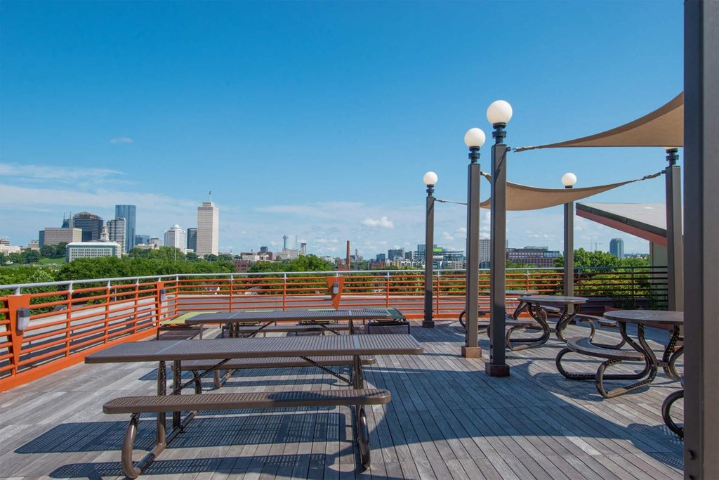 a deck with picnic tables and a view of the city