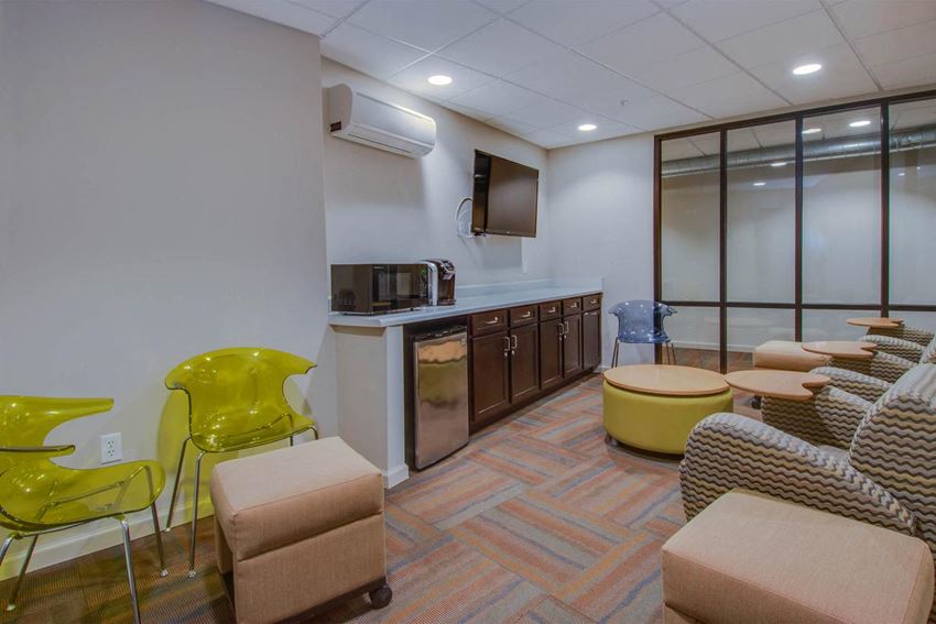 a living room with chairs and a kitchen and a television
