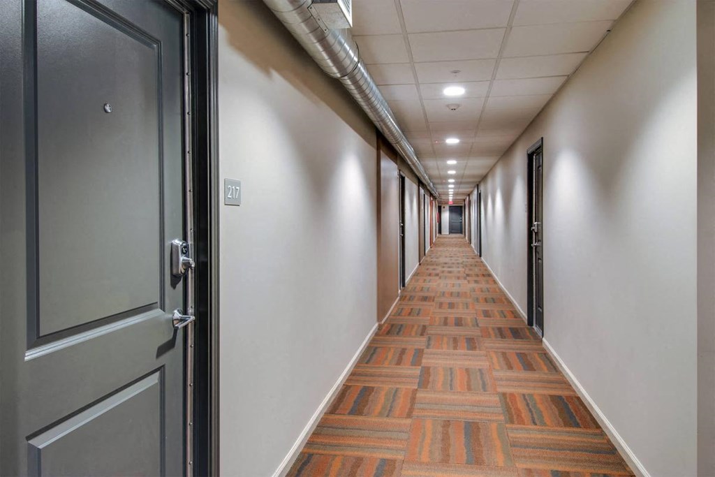 a long hallway with doors and a wood patterned floor