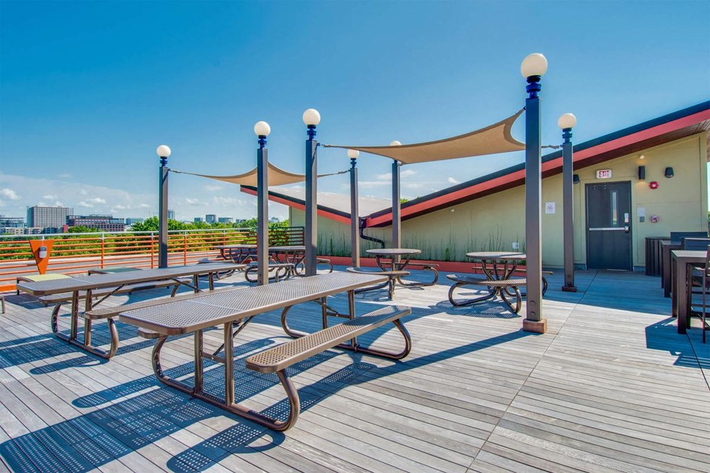 a patio with picnic tables and benches on top of a building