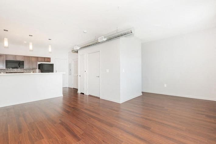 an empty living room and kitchen with a wood floor
