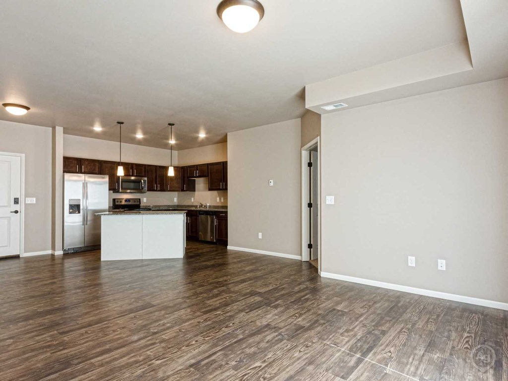 an empty living room and kitchen with wood flooring